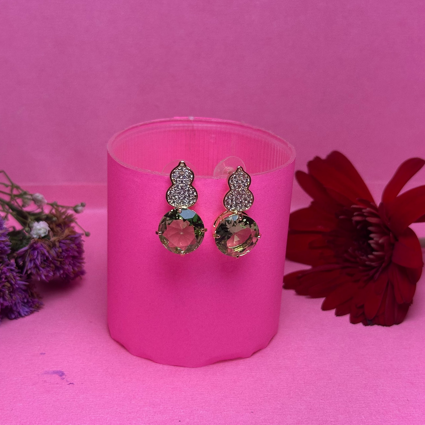 Earrings in a pink holder with flowers on a pink background