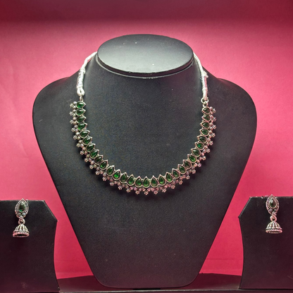 Necklace and earrings set on a black mannequin bust with a pink background