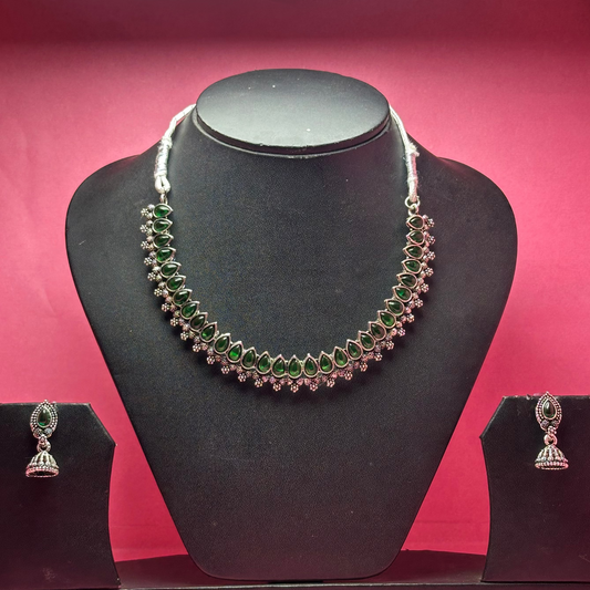Necklace and earrings set on a black mannequin bust with a pink background