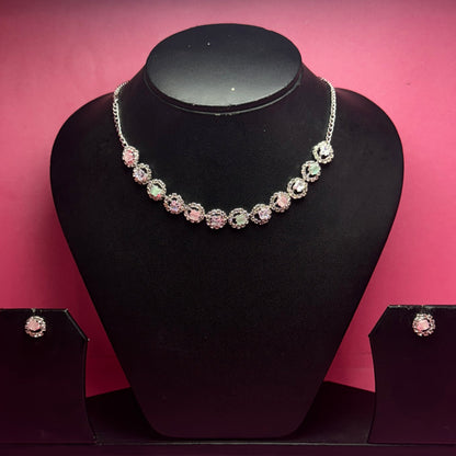 Black jewelry display with a bracelet and earrings against a pink wall