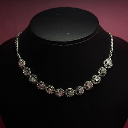 Silver necklace with clear stones on a black stand against a dark background